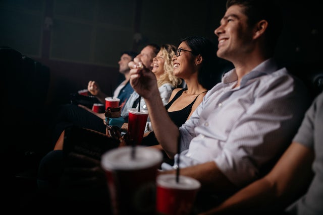 Happy people in a movie theater with drinks and snacks.
