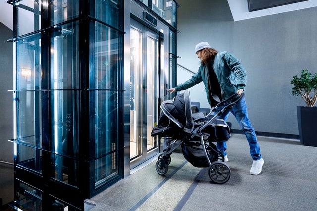 Man with a pram taking an elevator ride.