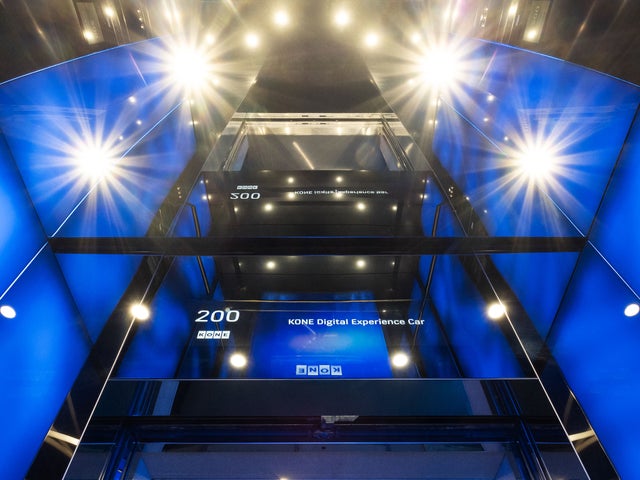 The inside of an elevator with dark blue lighting.
