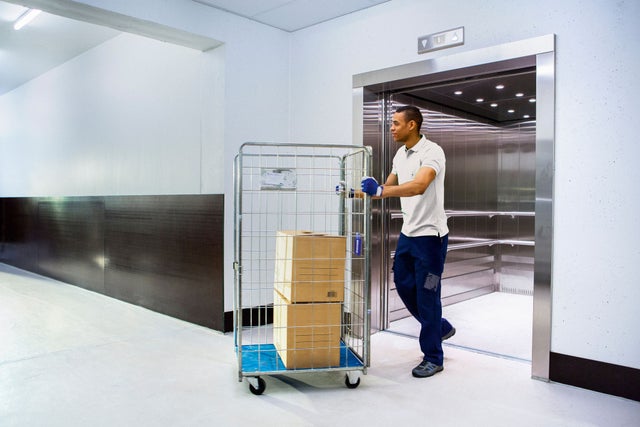 man coming out of an elevator with a packets rack