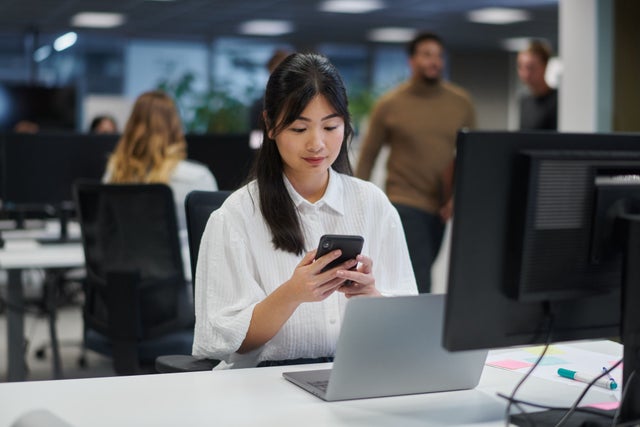 Woman sitting in an office looking at a phone