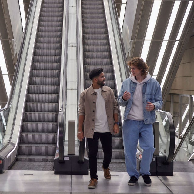 Two men walking off an escalator
