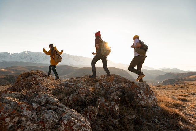 Three people hiking in a hilly landscape.