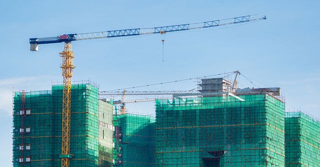 Building that has construction on the outside. Yellow crane on the left.