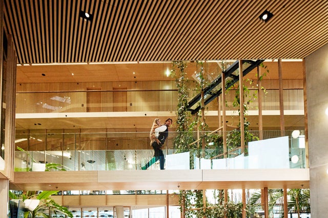 Mies, jolla on lapsi reppuselässä kävelee rakennuksessa sillalla.