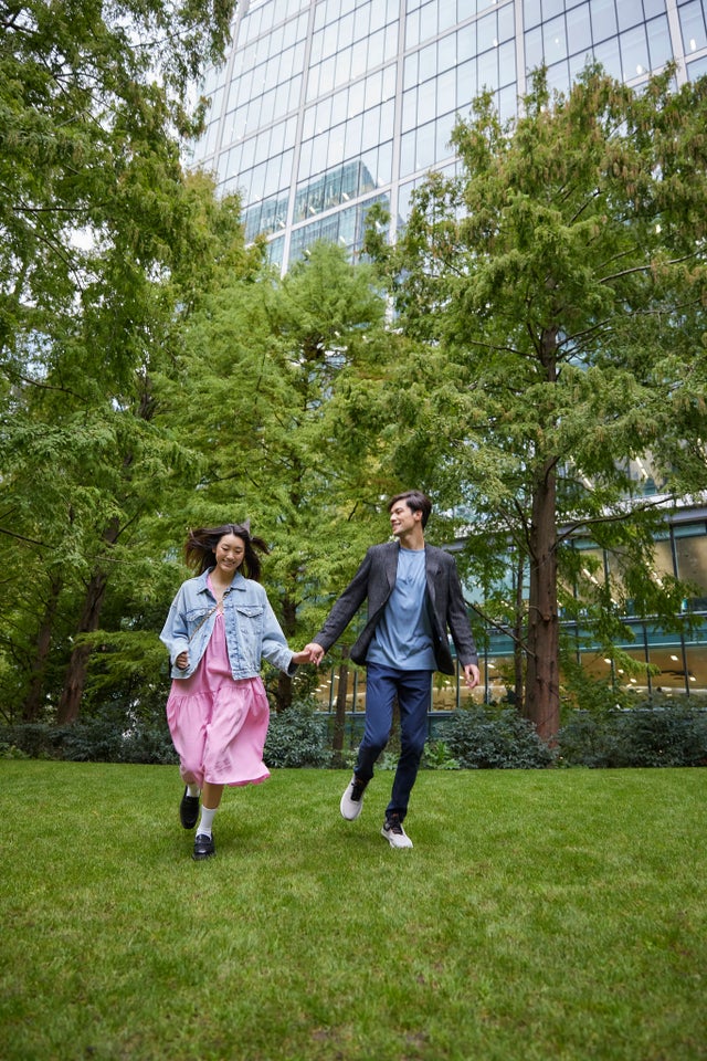 Happy Asian couple running in the park next to a high-rise building
