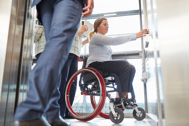 Woman in wheelchair in elevator pressing a button