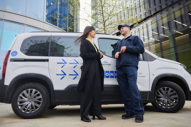 KONE technician talking to a customer in front of a KONE car