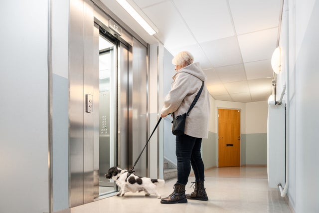 older woman with dog going in an elevator