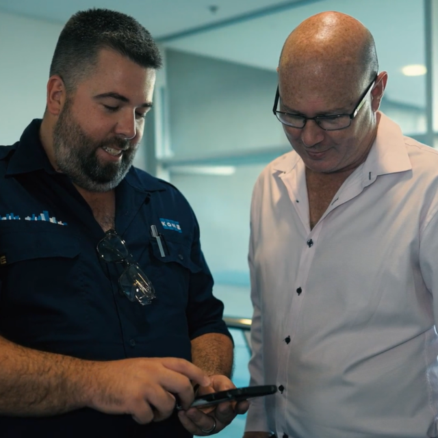 Sam White and another man looking at a phone