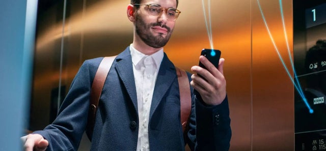 A man looking at a phone in an elevator