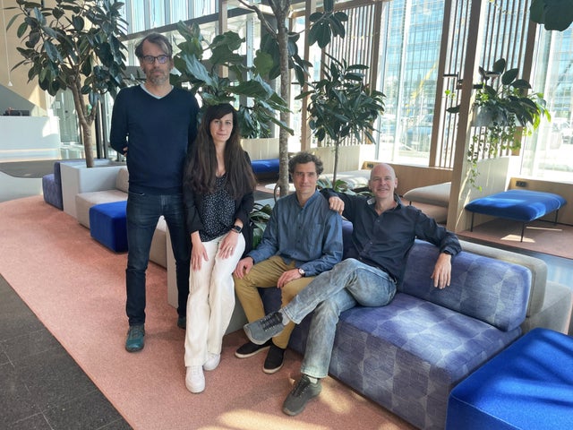 Three men and one woman at an office lobby.