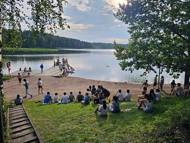 Several young people hanging out at a lakeshore.