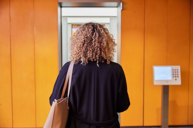 A woman with her back to the camera is waiting for the elevator.