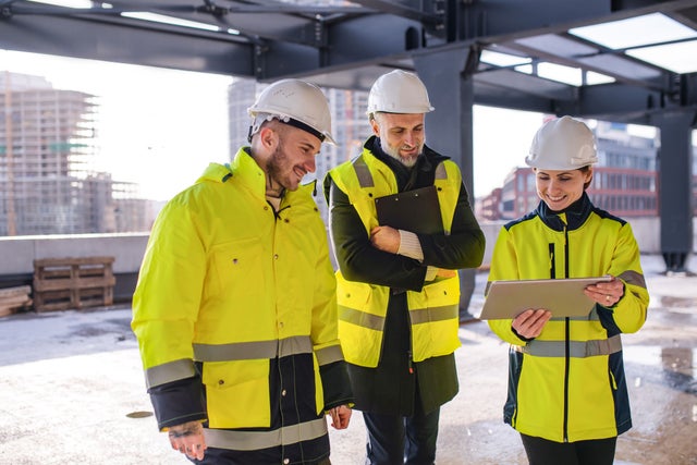 Two men and a woman visiting a construction site.