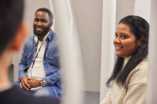 A smiling man and woman looking at a third person.