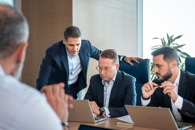 Businessmean with their laptops gathered at an office.