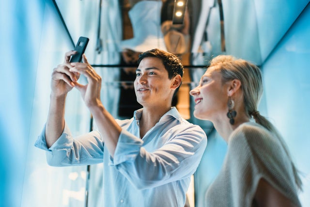 Young man and woman looking at a smartphone in an elevator.