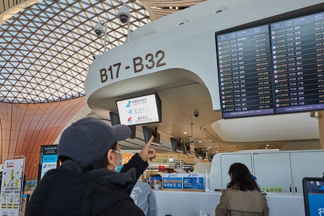 Man pointing at flight board in Beijing Daxing Airport