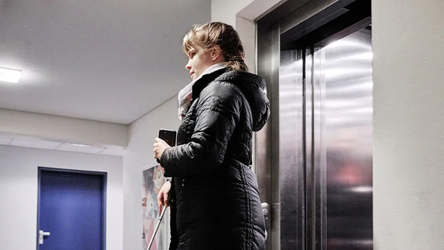 A blind girl stepping out of an elevator