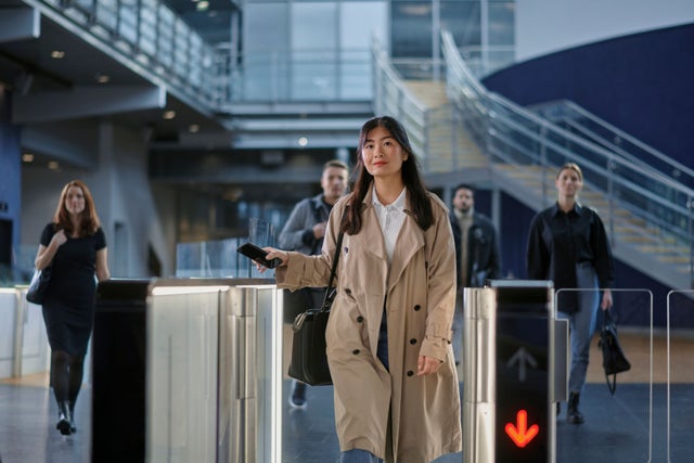 A woman walking through an access gate in a building lobby