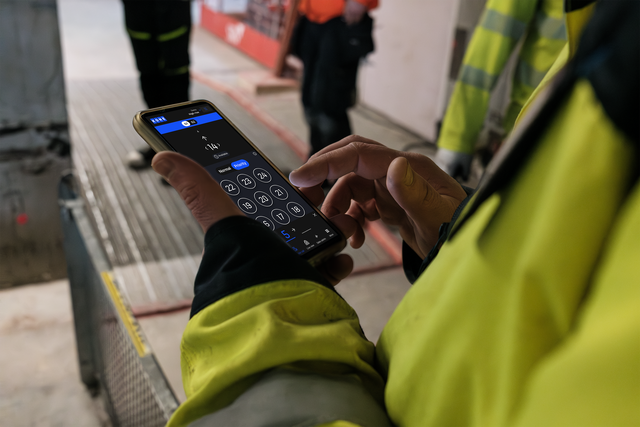Closeup of phone that has KONE SiteFlow open and a person is using it.