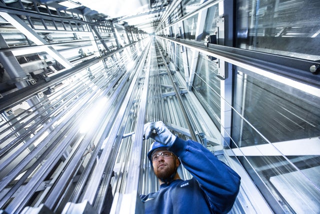 A worker standing at the bottom of a very high elevator shaft.
