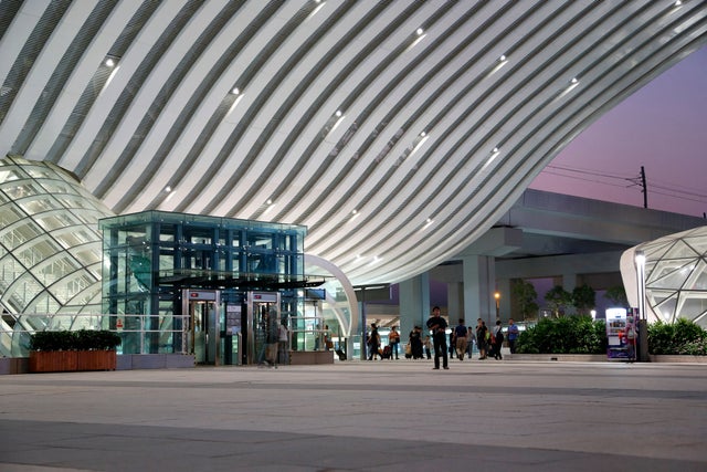 Overview of a station that has an elevator on the left and people walking around.