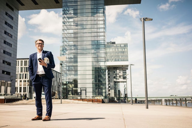 Man with phone standing in front of buildings