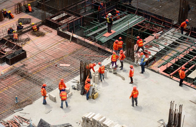 Construction site with loads of people wearing protective gear and high-visibility vests.