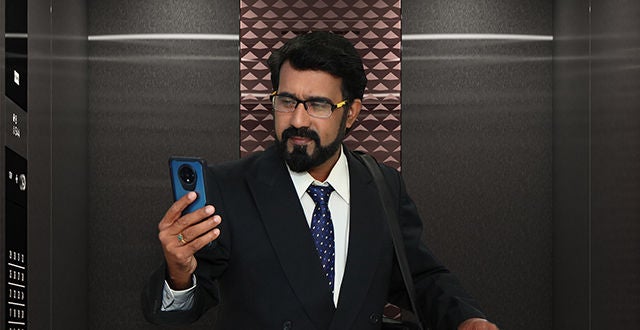 Business man in elevator looking at phone
