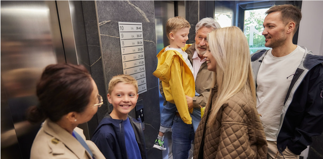 A family with grandparents, parents and young children in an elevator.