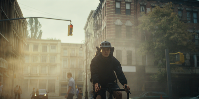 Man cycling in a city street with a helmet.
