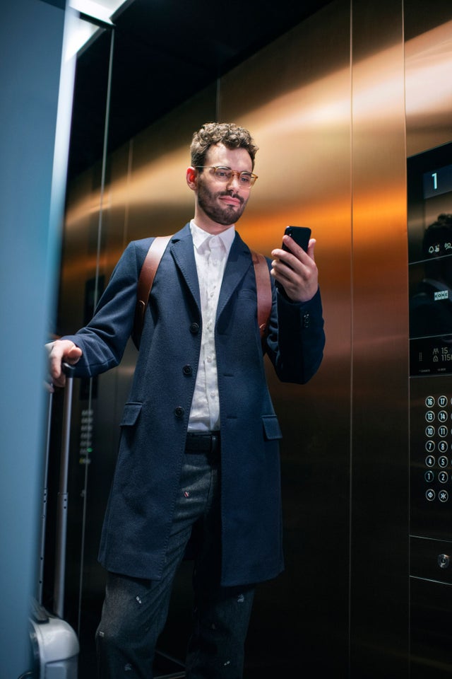 Man in elevator with mobile phone and luggage
