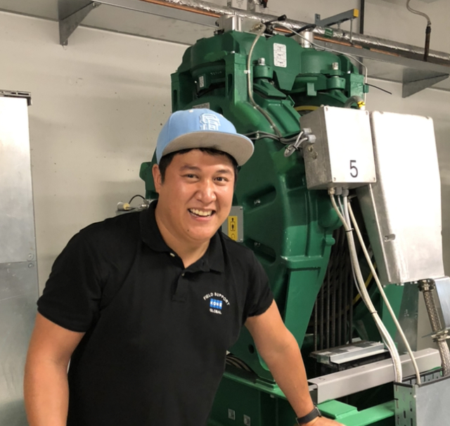 A smiling man in front of elevator machinery.