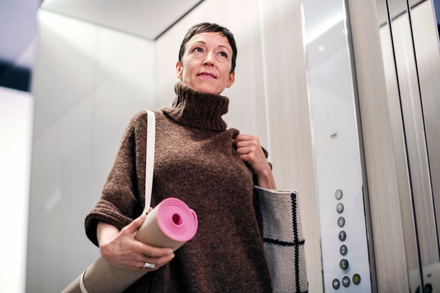A woman with a yoga mat in an elevator.