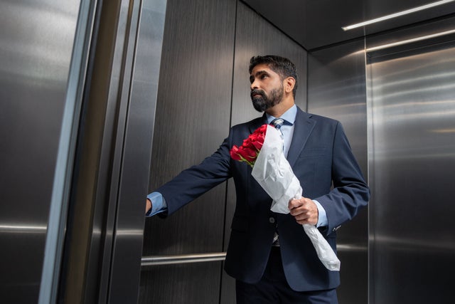 well dressed man holding flowers in an elevator