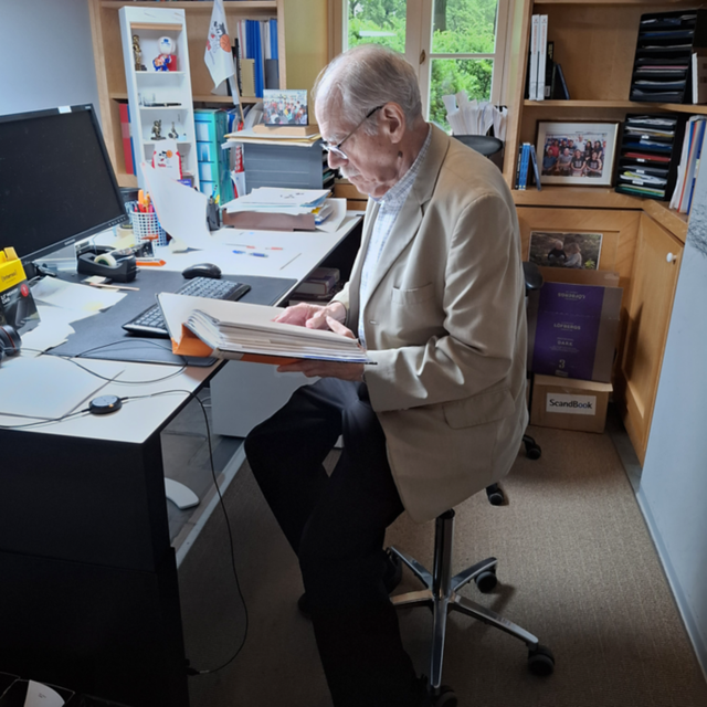 John Simon browsing papers at his office desk.