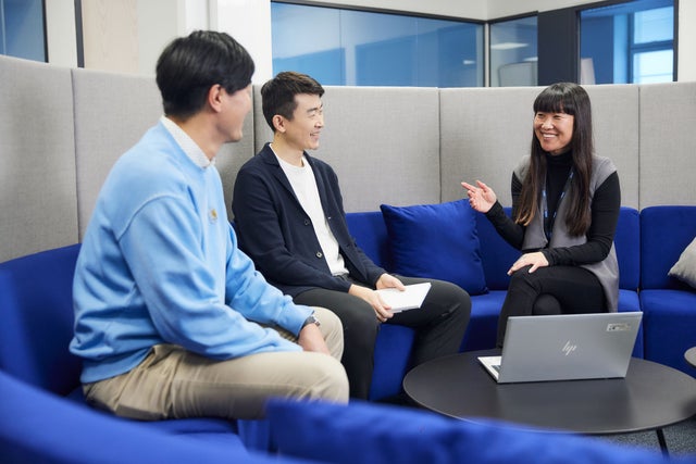 Three people sitting on an office sofa discussing