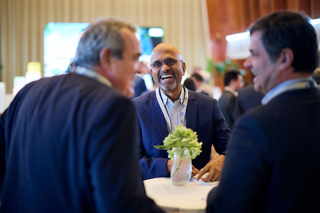 Three men in suits laughing at a meeting.