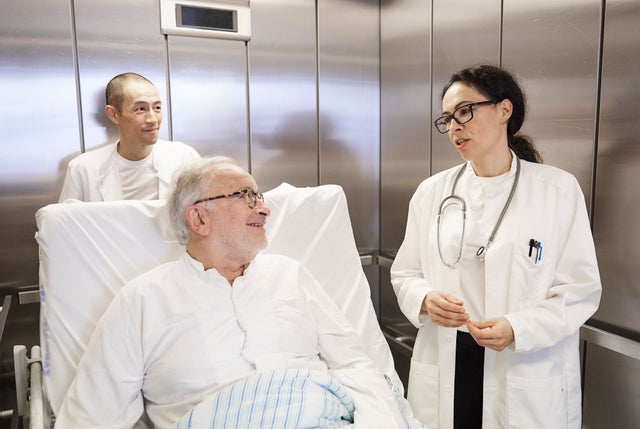 Hospital elevator with people and patient in bed