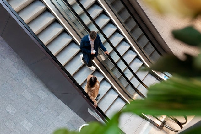 Two people going down the escalator.