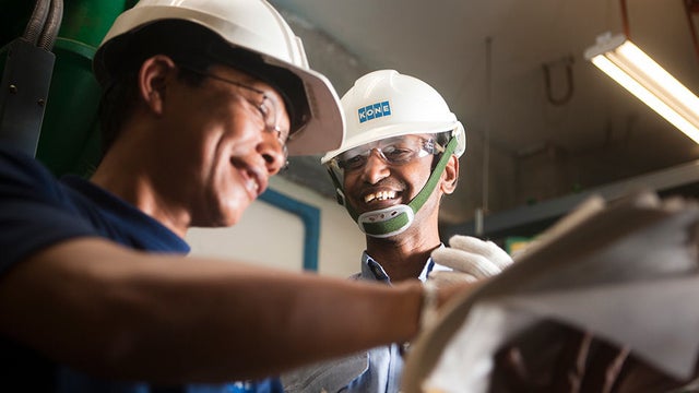  Two KONE factory workers smiling.