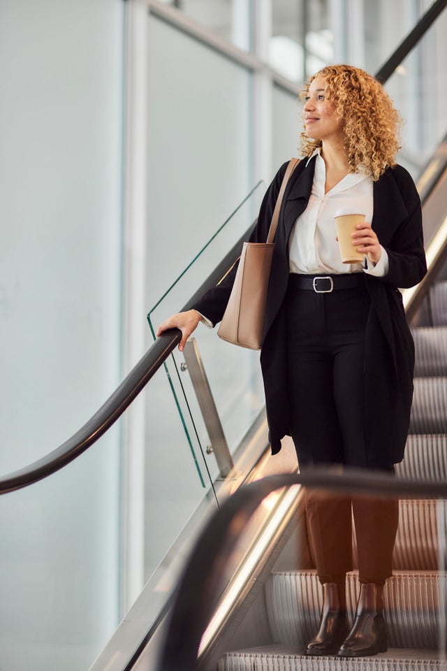 Woman on an escalator with coffee