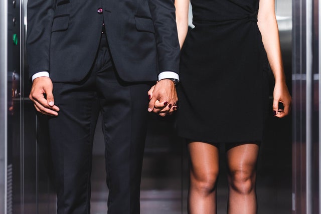 A man and a woman holding hands pictured from chest to knees.