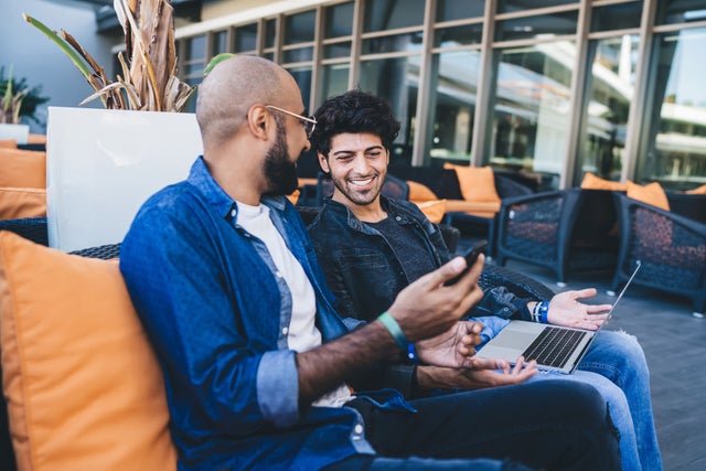 Two men with mobile phones on a sofa