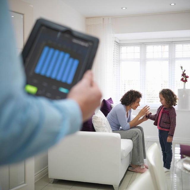 Woman and a child talking on a couch and a man with a tablet in front.