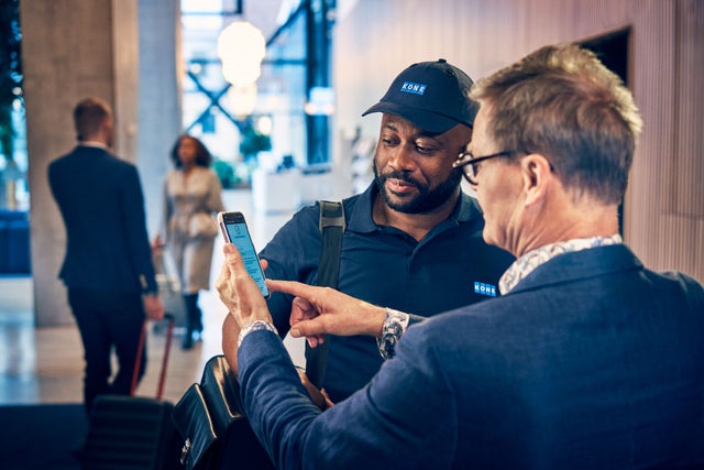 A KONE Technician with a customer and a service phone