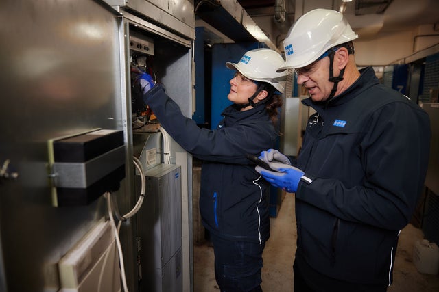 A woman and a man technician servicing an elevator.