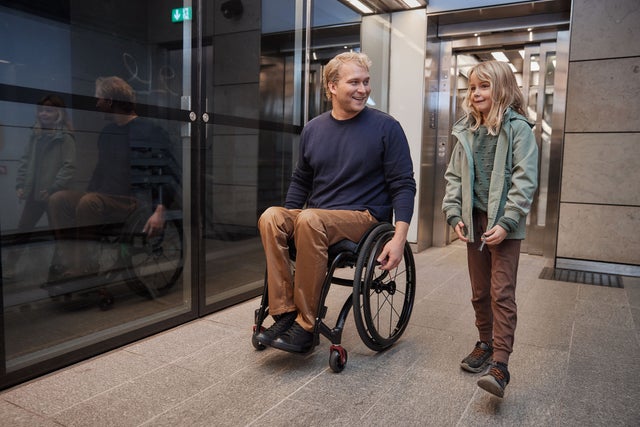 Man in wheelchair talking to a child.